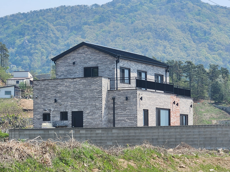 그레이 계열의 벽돌, 징크 지붕 (박공 스타일), 2층 테라스가 시원한 전원 주택