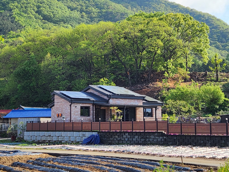 붉은 계열의 벽돌 마감과 징크 지붕, 태양광 난방 설치 "풍경화같은 집"